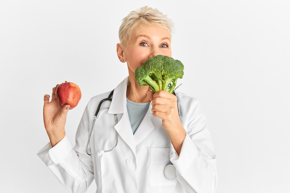 Mujer, en una mano con una manzana roja y en la otra brócoli. Nutrición y dietética 