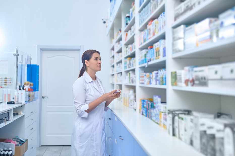 Mujer joven farmacéutica buscando un medicamento. Principios de la farmacología